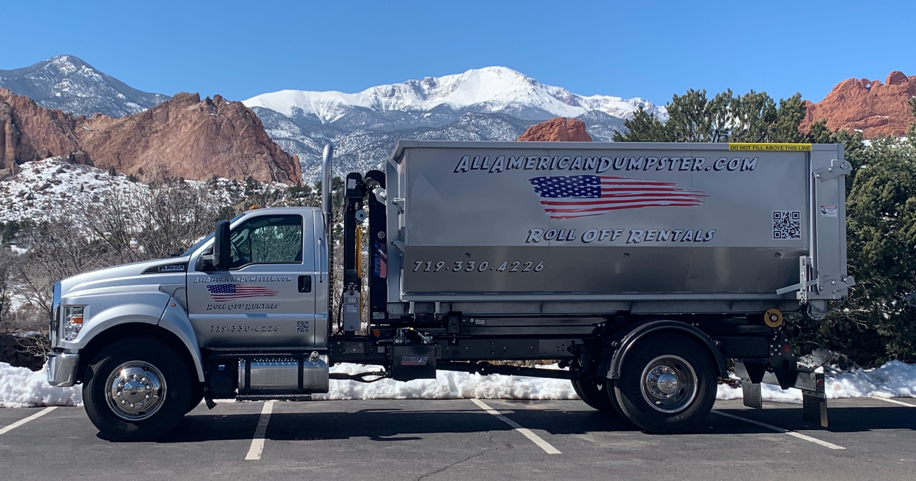 All American Dumpster roll-off truck in front of Pikes Peak, Colorado Springs